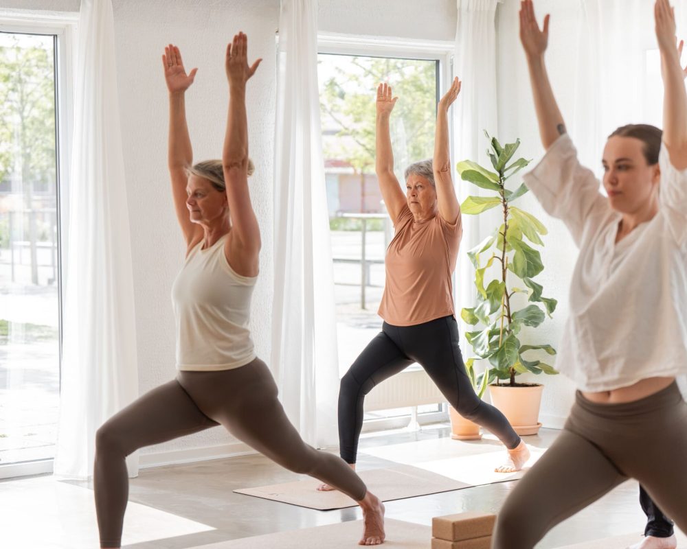 Deltagere udfører en dynamisk yogaøvelse på et yogahold i Silkeborg.